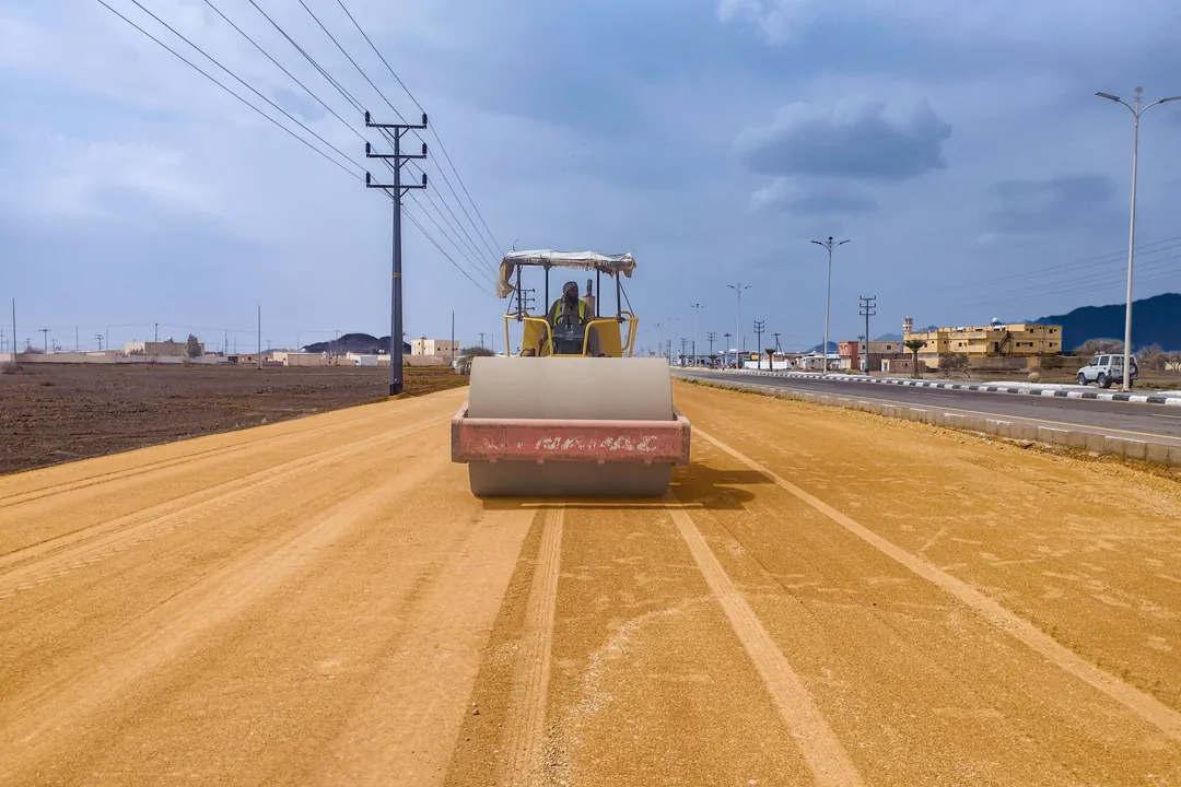 Rodillo compactando la capa de afirmado a lo largo de una vía en construcción