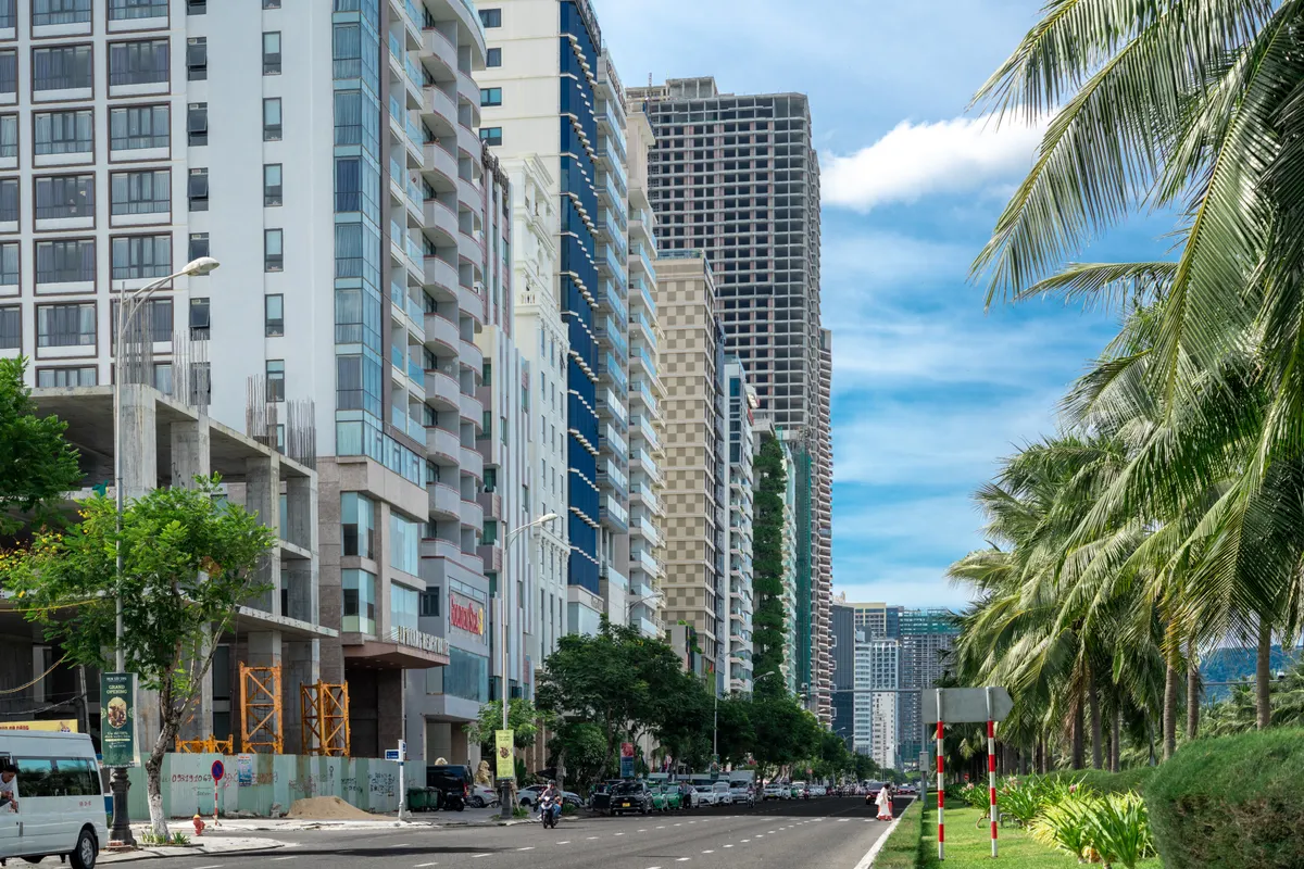 Edificios en construcción junto a una avenida con palmeras en una ciudad costera