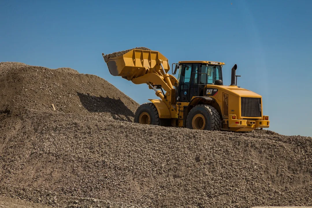 Cargador de ruedas tomando material granular del acopio para cargar la volqueta