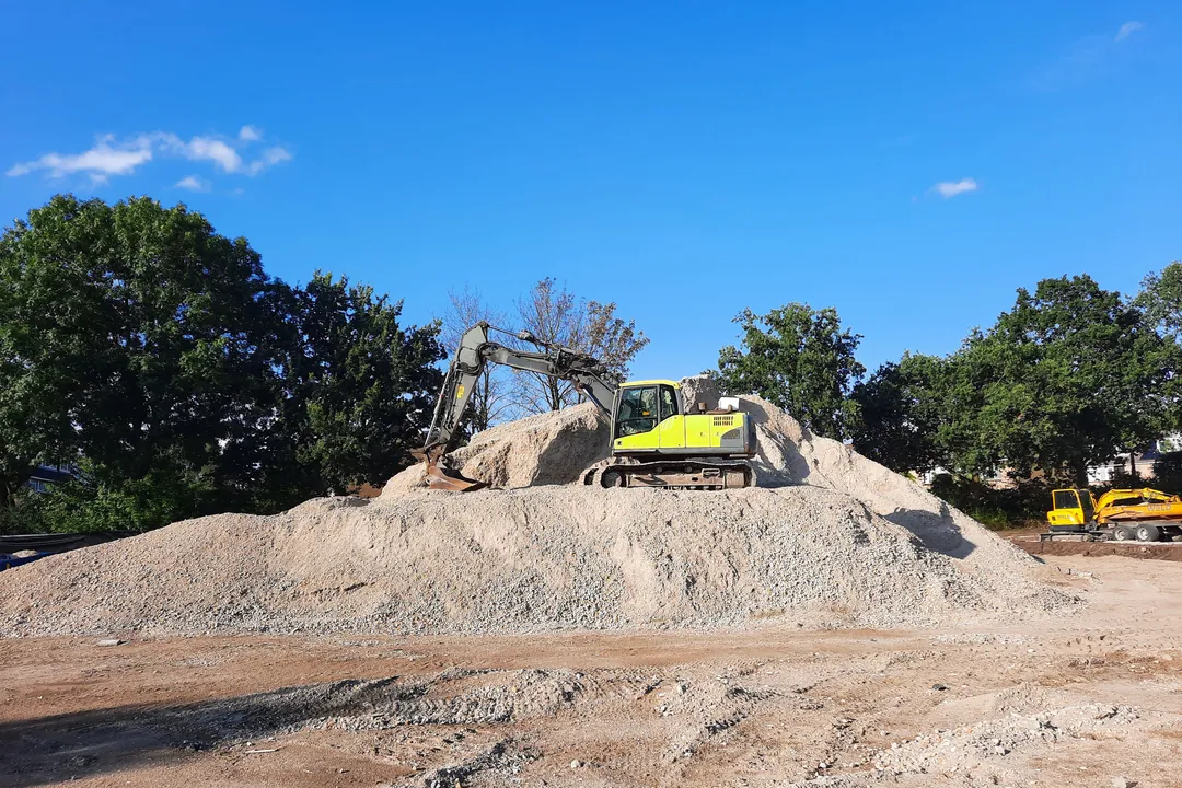 Excavadora trabajando sobre un acopio de gravilla bajo cielo despejado