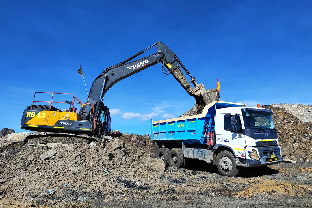 Excavadora cargando tierra sobre una volqueta durante el movimiento de tierras