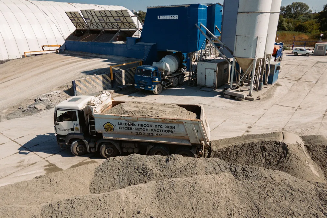 Planta de concreto con volqueta cargando junto a los acopios de agregados