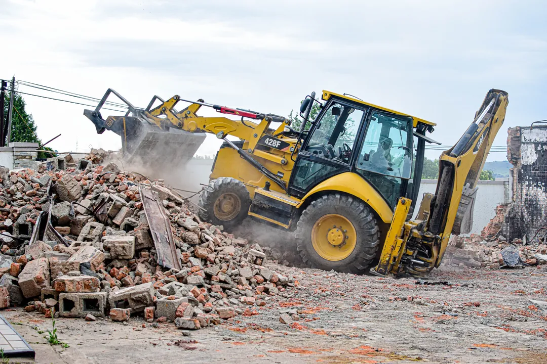 Retroexcavadora retirando escombros y residuos de demolición en un frente de obra