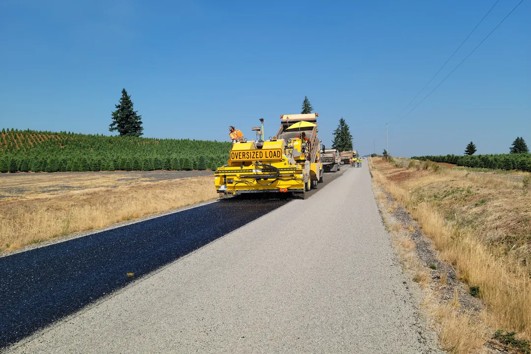 Maquinaria de pavimentación avanzando sobre la base granular de una vía rural